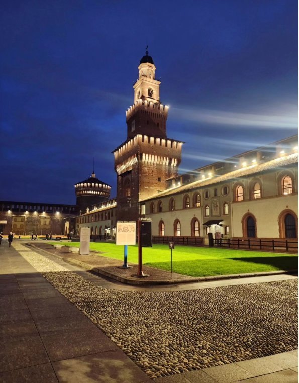 The Filarete Tower lit at dusk from the Cortile delle Armi